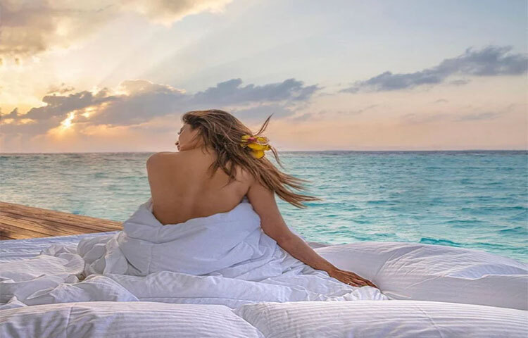 সমুদ্রের ধারে খোলা শরীরে মৌনি রায় ছুটিযাপন করছেন। সাদা কম্বলের নীচে ঢুকে একদৃষ্টে তাকিয়ে রয়েছেন নীল জলরাশির দিকে। ছবি: সংগৃহীত