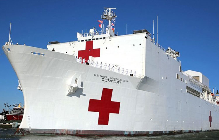 ধবধবে সাদা বিশাল জাহাজের সামনের অংশে লাল ক্রস চিহ্ন। ডকে দাঁড়ানো জাহাজের সামনে লাইন দিয়ে দাঁড়িয়ে পিপিই পরা নিরাপত্তাবাহিনী ও অ্যাম্বুলেন্স। দূরে ব্যাকগ্রাউন্ডে আইকনিক স্ট্যাচু অফ লিবার্টি। কিছুটা এমনই ছবি এখন ম্যানহ্যাটানের ডকের। নিউইয়র্কে বাড়তে থাকা করোনাভাইরাস আক্রান্তদের জন্য এখন ব্যবহৃত হচ্ছে মার্কিন যুক্তরাষ্ট্রের আপদকালীন ভাসমান হাসপাতাল ‘ইউএসএনএস কম্ফোর্ট’।