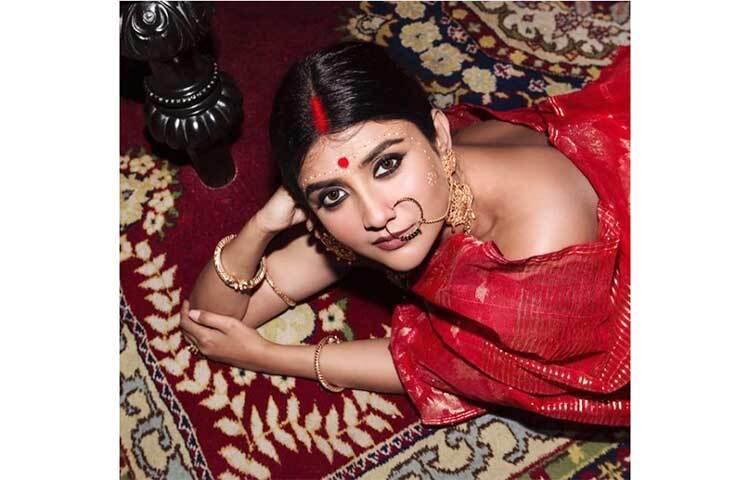 টুকটুকে লাল শাড়ি, সিঁথি ভর্তি সিঁদুর, কপালে সযত্নে আঁকা চন্দনের কলকা, লাল টিপ, গা ভর্তি সোনার সাবেকি গয়না, চোখে মোটা কাজল, নাকে ঝোলা নথ একেবারে কনের বেশে অভিনেত্রী পার্নো মিত্র। ছবি: ইনস্টাগ্রাম