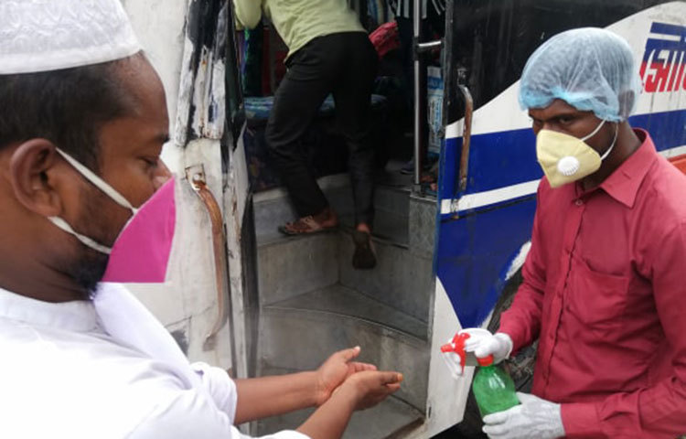 বাসে ওঠার আগে যাত্রীদের হাতে সেনিটাইজার দেয়া হচ্ছে। ছবি: মাহবুব আলম