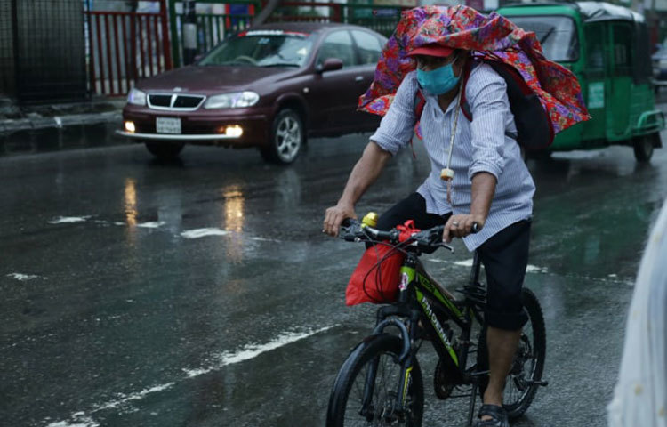 বৃষ্টি বাতাসে মাথার উপর থেকে উল্টে গেছে ছাতা। তার পরেও যেতে হবে কর্মস্থলে। ছবি: মাহবুব আলম