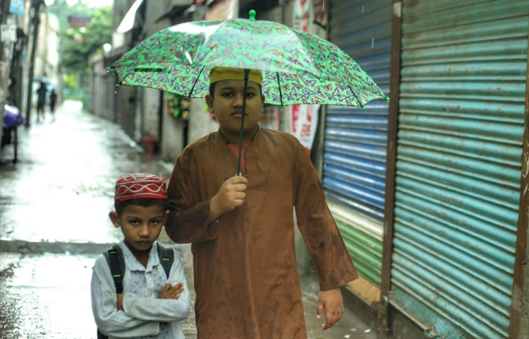 বৃষ্টির মধ্যেই ছাতা মাথায় বাইরে বের হয়েছে কোমলমতি শিশুরা।