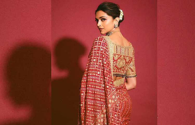 লাল রঙের একটি ডিজাইনার কাতান শাড়ি পরেছেন বলিউডের জনপ্রিয় অভিনেত্রী দীপিকা পাড়ুকোন। সোনালি রঙের জ্যামিতিক নকশা ও এমবেলিশমেন্ট করা শাড়িটির বিশেষ আকর্ষণ ছিল এর আঁচল। পুরো আঁচল জুড়ে সোনালি কারচুপির কাজ ও টিয়ারড্রপ পার্ল বসানো। নায়িকা শাড়িটির সঙ্গে পরেছেন ডিজাইনার ব্লাউজ। ছবি: ইনস্টাগ্রাম