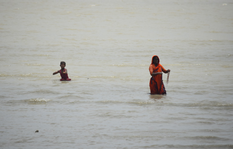 দেখতে দেখতে কোথা থেকে যেন সেই নারীর পাশে ভিড়ল একটি শিশু। ওর বয়স হবে ৮-১০। সে সাঁতার জানে। পানি মাড়িয়ে শিশুটি নারীর কাছে যেতেই হাত লাগাল জাল-রসিতে। বুঝলাম, শিশুটি তার মায়ের কাজে সাহায্য করতেই সেখানে গেছে। তখনও নদীর তীরে অপেক্ষা করছিলাম। বিষয়টি দেখতেই দাঁড়িয়েছি।