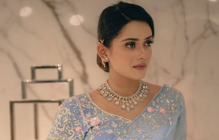 শাড়ির নরম রঙের সঙ্গে মিল রেখে গয়নার বাছাই ছিল মার্জিত ও অভিজাত। গলার স্টেটমেন্ট নেকলেসটি পুরো সাজে এনেছে রাজকীয় ছাপ। কানে ছোট দুল আর হাতে হালকা আঙটি সব মিলিয়ে তিনি যেন নিজের ব্যক্তিত্বের সঙ্গে সাজকে একেবারে নিখুঁতভাবে মিলিয়ে নিয়েছেন। ভারি গয়না নয়, বরং সঠিক গয়নাই কীভাবে লুককে উন্নত করতে পারে তার নিখুঁত উদাহরণ এটি।