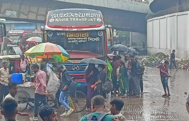 ছাতা মাথায় মালপত্র নিয়ে দাঁড়িয়ে থাকা মানুষগুলোর চোখে-মুখে ক্লান্তি আর হতাশার ছাপ স্পষ্ট।
