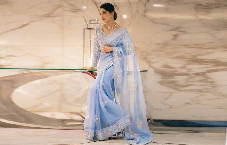 চুল বাঁধা হয়েছে শৈল্পিক বান স্টাইলে পরিপাটি, সিম্পল অথচ ক্ল্যাসিক। যা তার মুখের আকৃতি ফুটিয়ে তুলেছে আরও পরিষ্কারভাবে। নরম মেকআপ, স্নিগ্ধ টোন, আর স্বাভাবিক গ্লো সব মিলিয়ে তার উপস্থিতিটি হয়ে উঠেছে অত্যন্ত মার্জিত।