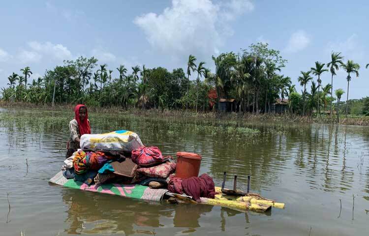 ঘর হারিয়ে ভেলায়  মালামাল নিয়ে ঘুরছেন এক তরুণী। ছবি: আরিফুর রহমান