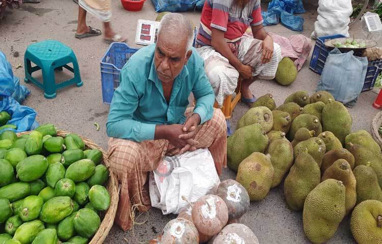 রোদের মধ্যেই বিক্রির জন্য ফল সাজিয়ে বসে আছেন এক ব্যবসায়ী।  ছবি: মাহবুবুল ইসলাম পলাশ