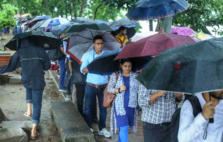 বাস স্টপেজগুলোতে শত শত মানুষ ছাতা মাথায় দাঁড়িয়ে আছে গাড়ির জন্য। ছবি: মাহবুব আলম