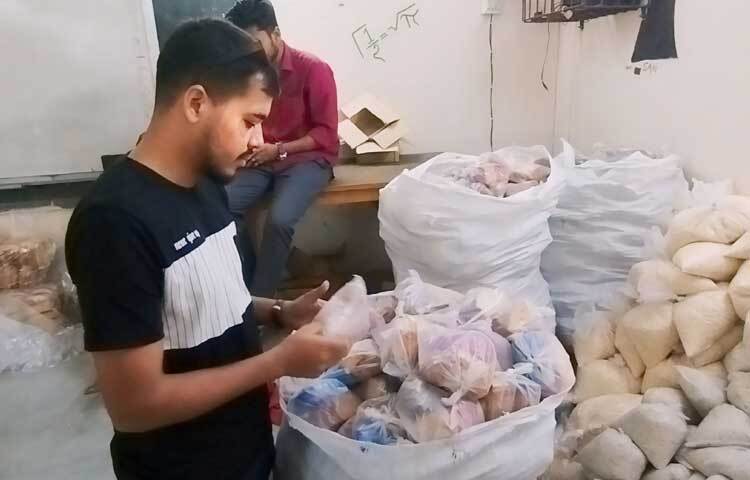কারো হাতে রয়েছে চিড়া ভর্তি প্যাকেট, কেউ ব্যস্ত মুড়ি প্যাকেজিংয়ে, আর কেউ ওষুধ গুছিয়ে রাখছে। সবার কাজই ভাগ করে দেওয়া হয়েছে যাতে দ্রুততার সঙ্গে সব কাজ সম্পন্ন করা যায়। ছবি: মামুনূর রহমান হৃদয়