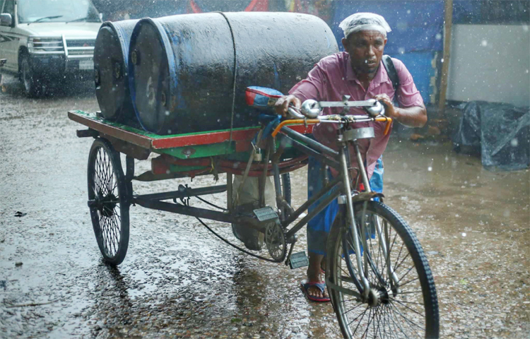 বৃষ্টিতে ভিজে জ্বালানিবাহী ভ্যান নিয়ে গন্তব্যের দিকে পা বাড়িয়েছেন একজন ভ্যানচালক। বৃষ্টি থামার জন্য অপেক্ষা করার সুযোগ নেই তার। ছবি: মাহবুব আলম