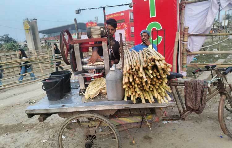 মেলায় প্রবেশের আগে গেইটের কাছেই আখের রস বিক্রি করছেন দোকানি।