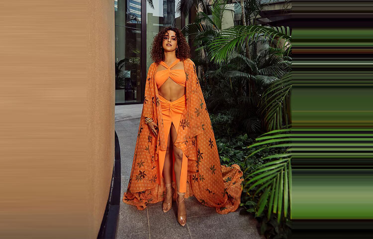 গেরুয়া রঙের স্লিট স্কার্ট, বিকিনি টপ আর সঙ্গে লং জ্যাকেটে বেশ স্টাইলিশ লাগছে তাকে।