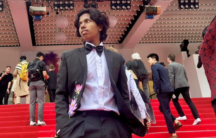 নীলচে ধূসর জ্যাকেটের ল্যাপেল থেকে শুরু করে জ্বলজ্বল করছে শাপলা ফুলের এমবেলিশমেন্ট। জাতীয় ফুলের এই ছোঁয়া যেন কান উৎসবের মঞ্চেই বাংলাদেশকে বিশ্বমঞ্চে আলোকিত করছে।