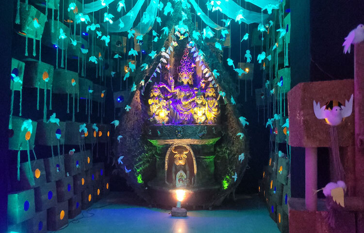 মণ্ডপের প্রবেশপথ সাজানো হয়েছে পাখির পালকের মোটিফে। নারকেলের ছোবড়া দিয়ে বাবুই পাখির বাসার আদলে তৈরি মণ্ডপে বসানো হয়েছে দুর্গার প্রতিমা। তারপর একটু ভেতরেই মশারির কাপড়ে অনেকগুলো পাখি বসে আছে। এর তিন পাশে কার্টন ও কাঠের গুড়া দিয়ে সাজানো হয়েছে শতশত পাখির বাসা। বাসা থেকে উঁকি দিচ্ছে পাখিরা। তুলা ও কাগজে তৈরি পাখিদের ঝাঁক যেন মনে করিয়ে দিচ্ছে কিচিরমিচির মধুর শব্দ।