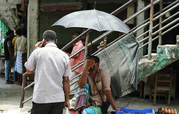 ছাতা মাথায় ফুটপাতে দোকান সাজিয়ে বসেছেন ব্যবসায়ী। ছবি: মাহবুব আলম