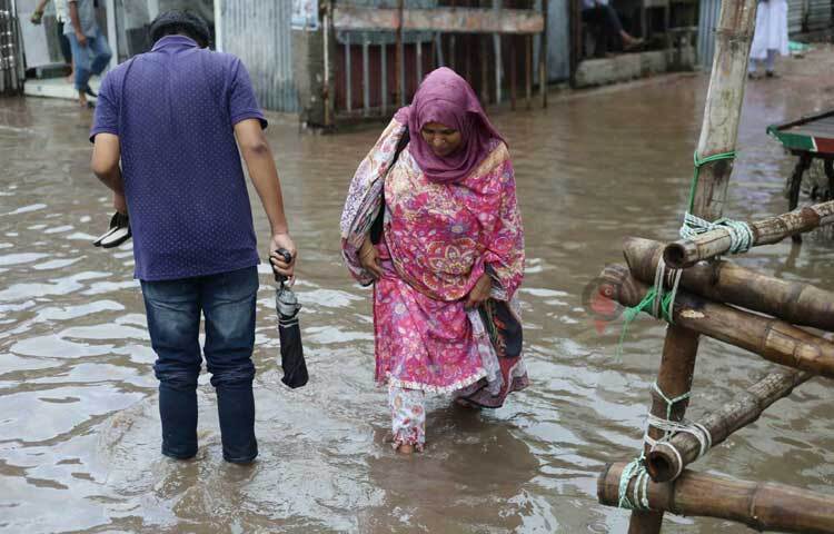 হাঁটু পানি মাড়িয়েই চলাচল করছেন পথচারীরা। ছবি: মাহবুব আলম