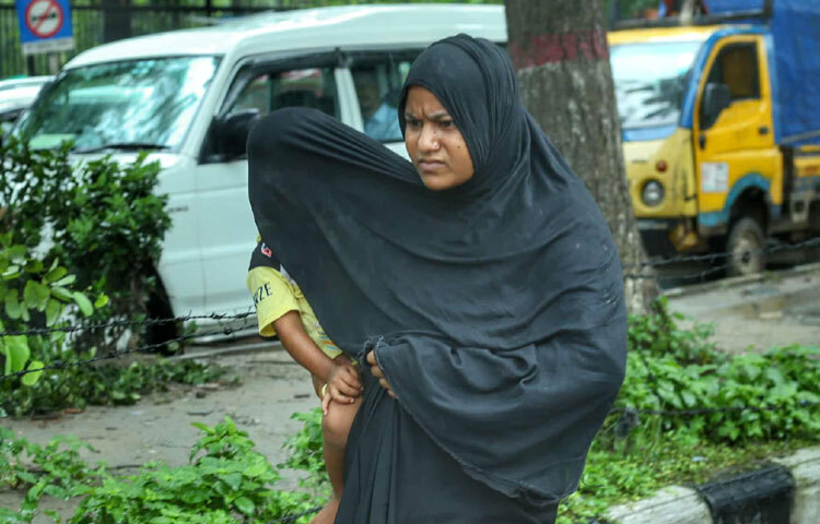 সন্তানকে বৃষ্টির পানি থেকে বাঁচানোর আপ্রাণ চেষ্টা মায়ের।