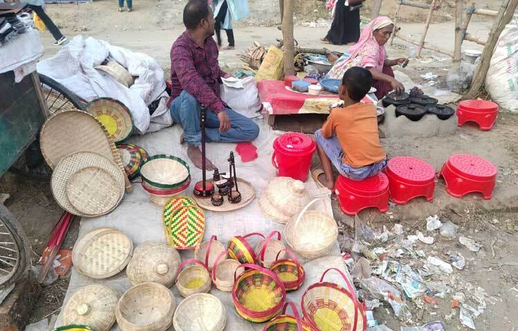 বাঁশ ও বেতের তৈরি জিনিস নিয়ে এসেছেন এক বিক্রেতা। পাশেই পিঠা বানাচ্ছেন নারী।