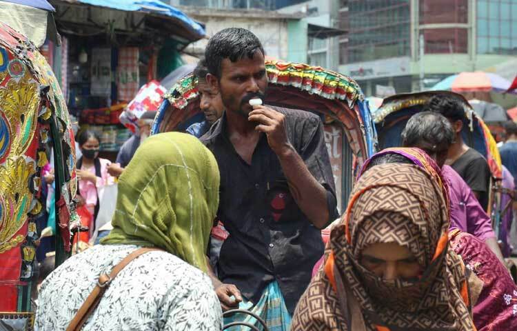 গরমে একটু স্বস্তির আশায় আইসক্রিম খেতে খেতে রিকশা চালাচ্ছেন চালক। ছবি: মাহবুব আলম