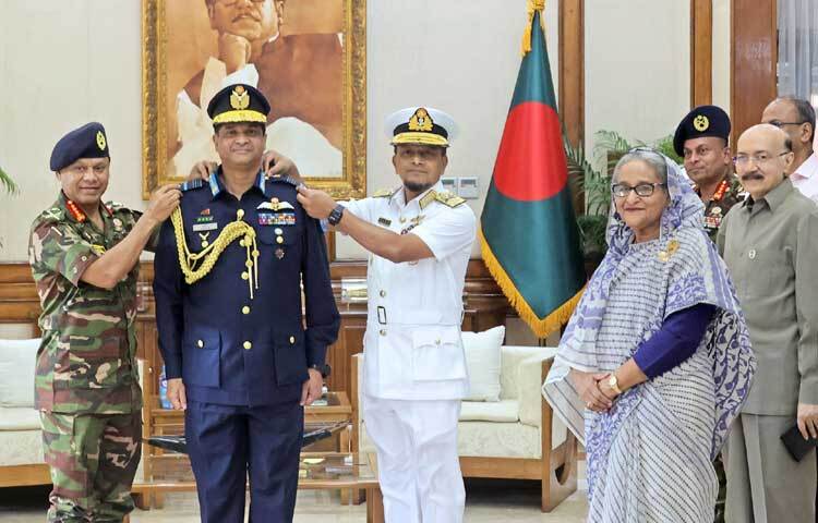 আজ  গণভবনে প্রধানমন্ত্রী শেখ হাসিনার উপস্থিতিতে সেনাবাহিনী প্রধান ও নৌবাহিনী প্রধান নবনিযুক্ত বিমানবাহিনী প্রধান এয়ার মার্শাল হাসান মাহমুদ খাঁনে র‌্যাংক ব্যাজ পরিয়ে দেন। র‌্যাংক ব্যাজ পরিধানের পর নবনিযুক্ত বিমানবাহিনী প্রধানকে ফুল দিয়ে অভিনন্দন জানান প্রধানমন্ত্রী। ছবি: ইয়াসিন কবির জয়