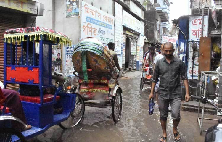 কেউ ছাতা কেউবা রেইনকোট পরে গন্তব্যে যাচ্ছেন। ছবি: বিপ্লব দীক্ষিত