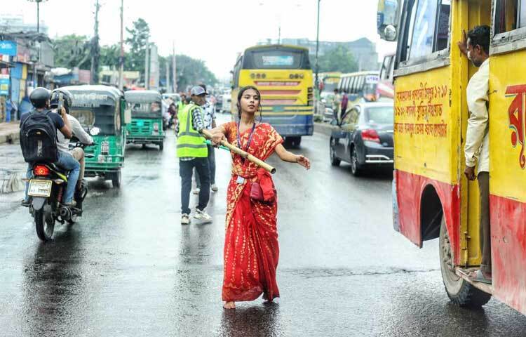রোডের মাঝখানে দাঁড়িয়ে গাড়ির লেন ঠিক রাখতে ব্যস্ত ফাহমিদা। ছবি: মাহবুব আলম