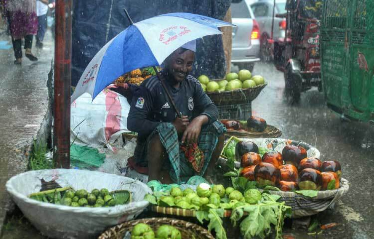 বৃষ্টির মধ্যেই দোকান সাজিয়ে বসেছেন ব্যবসায়ী। ছবি: মাহবুব আলম