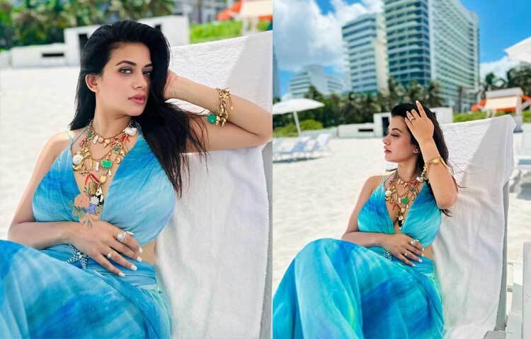 ফ্লেয়ার প্যাটার্নের নীল ড্রেসের সঙ্গে বোহো স্টাইলের শামুক-ঝিনুক আর বর্ণিল পাথরের নেকপিস ও ব্রেসলেট পরেছেন লাস্যময়ী এই নায়িকা।