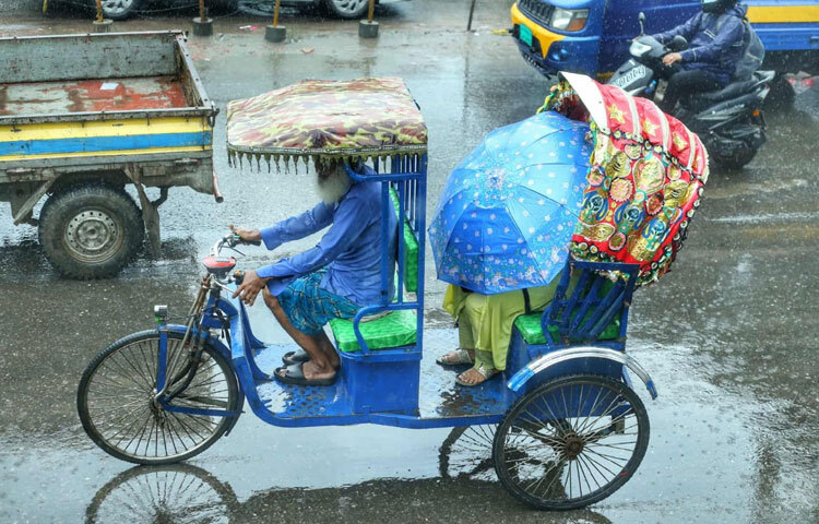 কেউ ছাতা মাথায় তুলে কাজে বের হয়েছেন, কেউ রেইনকোটে ভরসা রেখেছেন। আর কেউ আছেন, শুধুই বৃষ্টির সঙ্গে মিশে রিকশায় যাত্রী টানছেন।