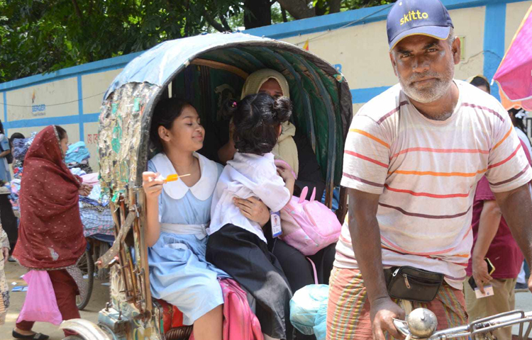 স্কুল ছুটি হলে সন্তানদের নিয়ে রিকশায় বাড়ি ফিরছেন মা। ছবি: বিপ্লব দীক্ষিত