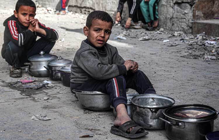 খাবারের আশায় বসে আছে শিশুরা। ছবি: এএফপি