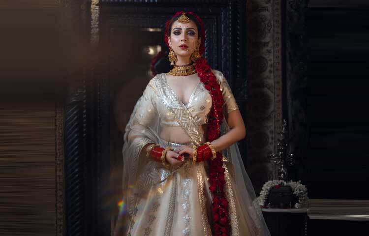 সাদা লেহেঙ্গা আর চুলে লাগানো গোলাপে দারুণ লাগছে তাকে।