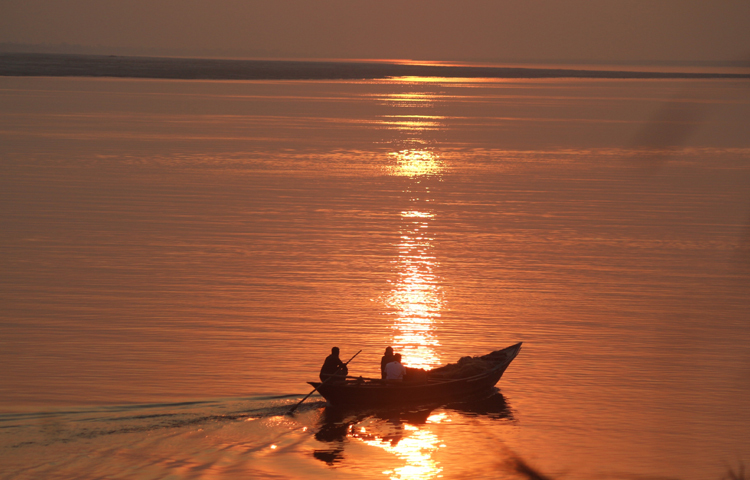 পদ্মা নদীর মাঝে নৌকায় বসে সূর্যাস্ত উপভোগ করছেন কয়েকজন প্রকৃতিপ্রেমী। ছবি: আরমান খান