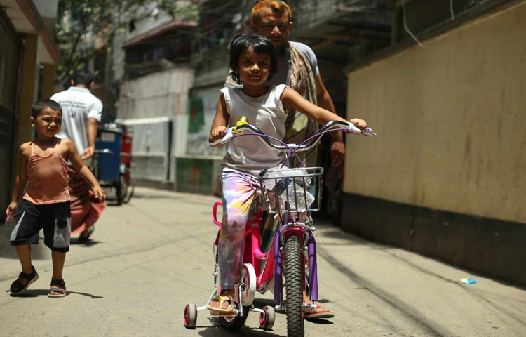 ছুটিতে মেয়েকে সাইকেল চালানো শেখাচ্ছেন বাবা। ছবি: মাহবুব আলম