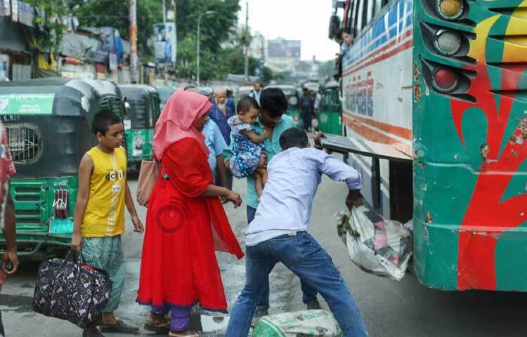 হেলপারের সাহায্যে বাস থেকে নিজেদের ব্যাগ নামিয়ে নিচ্ছেন যাত্রীরা। ছবি: মাহবুব আলম