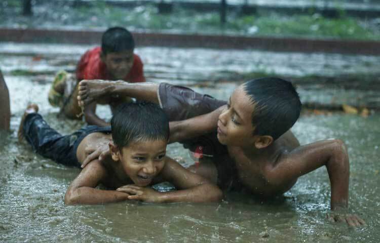 বৃষ্টির মধ্যেই খেলায় মগ্ন অবুঝ শিশুরা। ছবি: মাহবুব আলম