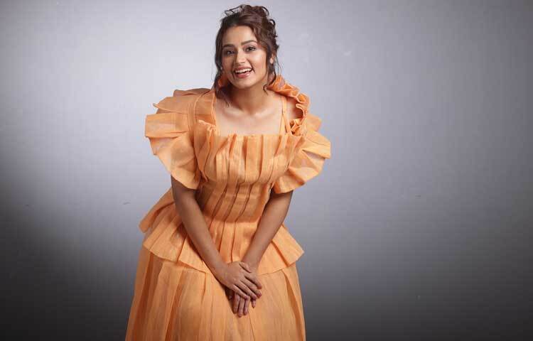 হালকা কমলা রঙের প্লিটেড ডিজাইন করা স্ট্রাকচার্ড গাউনে লাস্যময়ী ফারিণ।