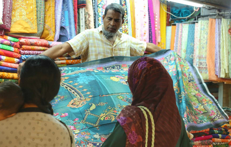 ক্রেতাদের পোশাক দেখাচ্ছেন দোকানি।