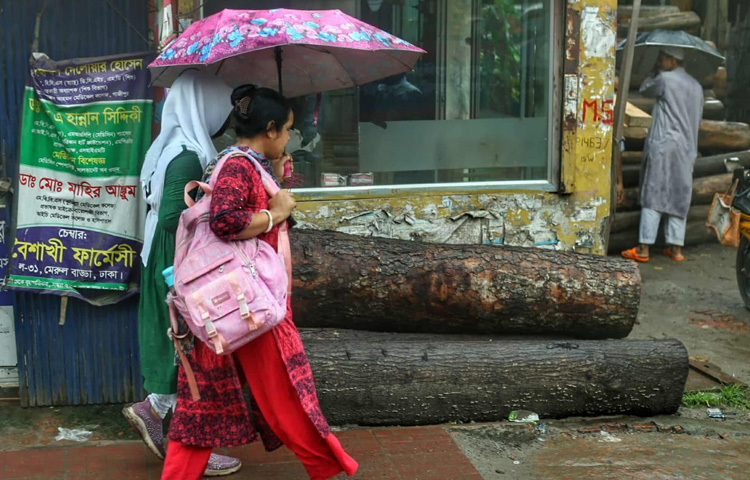 বৃষ্টির মধ্যেই সন্তানকে স্কুলে নিয়ে যাচ্ছেন এক মা।