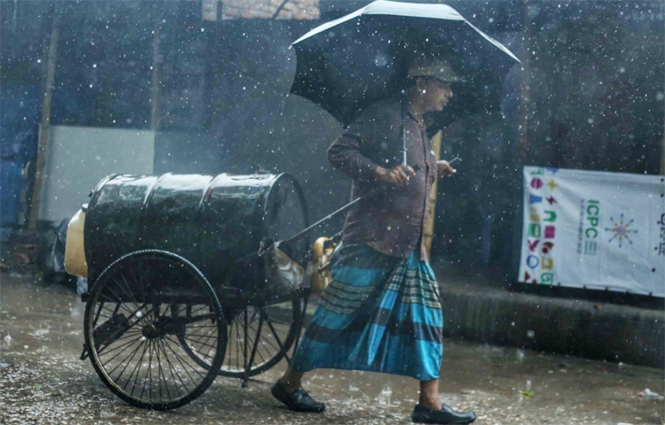 দুই চাকার গাড়িতে জ্বালানি কিংবা ভোজ্যতেল নিয়ে গন্তব্যে ছুটছেন তিনি। মাথায় ধরে আছেন ছাতা। অতিবৃষ্টিতেও ঘরে বসে থাকার উপায় নেই এমন শ্রমজীবীর। ছবি: মাহবুব আলম