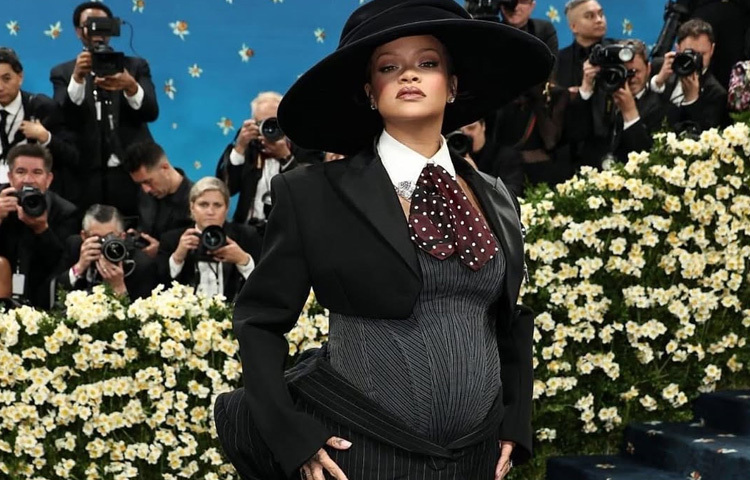 রেড কার্পেটে রিহানার চলন আর গাউনটির কাট এমনভাবে ডিজাইন করা হয়েছিল যাতে বেবি বাম্প স্পষ্ট দেখা যায়। কোনো ভান নেই, নেই ঢাকার চেষ্টা বরং সেই মৃদু উঁচুতা ছিল ফ্যাশনের হৃদয়কেন্দ্র। একনজরে মনে হতে পারে ওভার দ্য টপ, কিন্তু ফ্যাশন বোদ্ধারা বলছেন; এই লুকটা ছিল একদম সময়োপযোগী, সাহসী এবং চমৎকার।