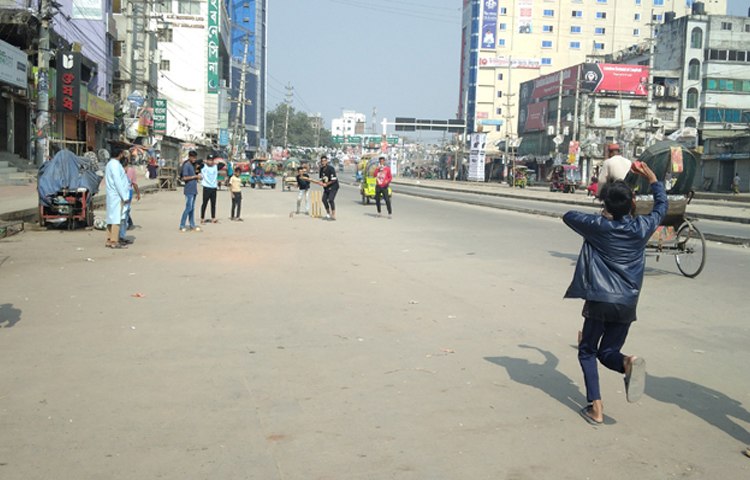 ঢাকার কেরানীগঞ্জের বাবুবাজার ব্রিজের সামনে ফাঁকা রাস্তা পেয়ে ক্রিকেট খেলায় মেতেছেন কয়েকজন তরুণ। ছবি: জাগো নিউজ