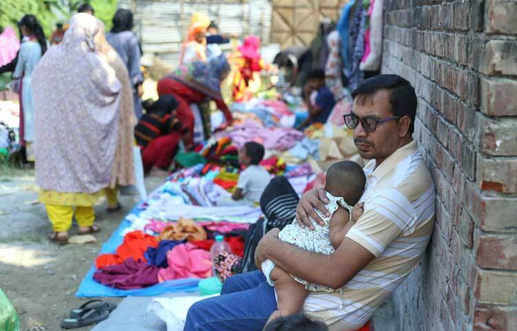 স্ত্রী কেনা-কাটায় ব্যস্ত। সন্তান কোলে বসে আছেন এক ব্যক্তি।