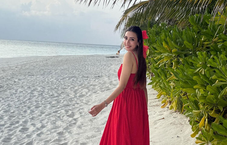 নুডল স্ট্র্যাপের লাল মিডি ড্রেসে সমুদ্রপাড়ে ঘুরে বেড়াচ্ছেন তিনি।