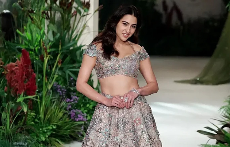 র‍্যাম্পে সারার পদার্পণ মানেই এক অনন্য অভিজাততা। তার পরনে থাকা লেহেঙ্গা ছিল ট্র্যাডিশনাল, কিন্তু তাতে যুক্ত হয়েছে প্রকৃতি অনুপ্রাণিত মোটিফ-যেন জঙ্গল ঘেরা এক রূপকথার রাণী। ফুল, পাতার নিপুণ সূচিকর্ম, পোশাকের বুনোটে ঘেরা এক বুনো সৌন্দর্য; সব মিলিয়ে ছিল এক চিত্রনাট্য, যেখানে সারা হলেন কেন্দ্রীয় চরিত্র।