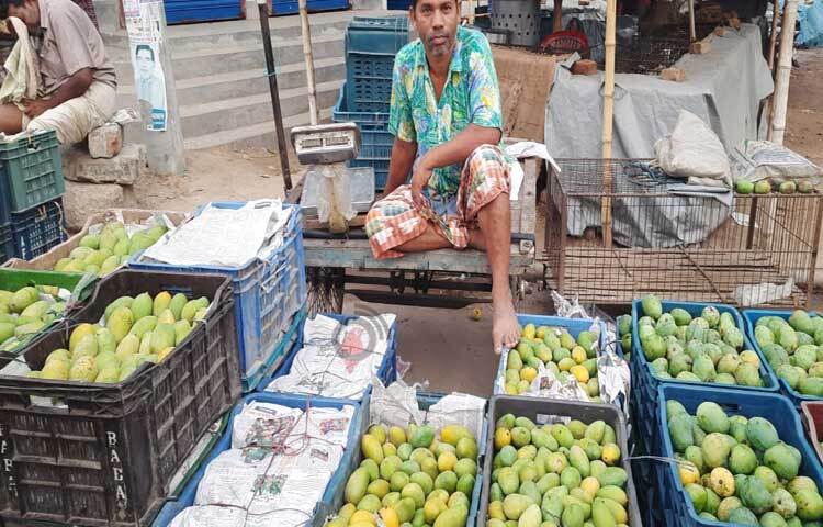 আম সাজিয়ে ক্রেতার আশায় বসে আছেন ব্যবসায়ী। ছবি: মাহবুবুল ইসলাম পলাশ