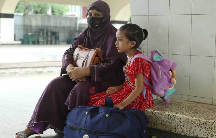 সন্তানকে নিয়ে স্টেশনে বসে আছেন মা। ছবি: মাহবুব আলম