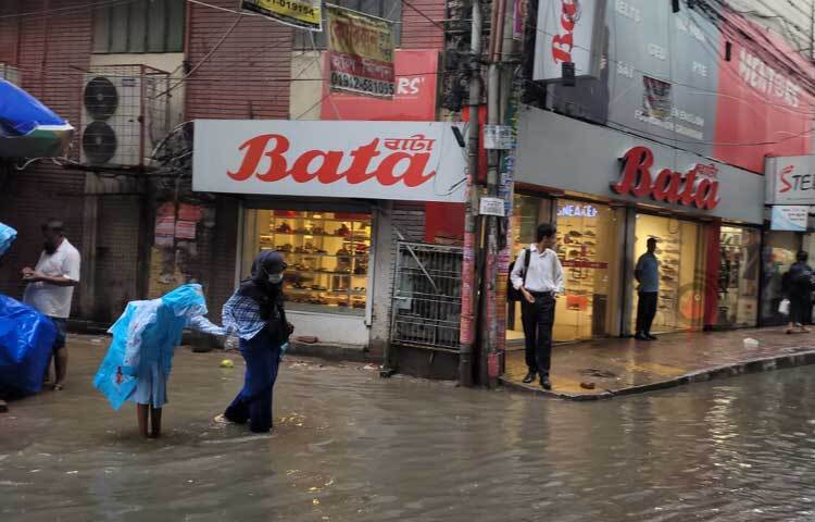 সড়কে জমে থাকা পানি মাড়িয়েই সন্তানকে স্কুল থেকে নিয়ে ফিরছেন মা। ছবি: রায়হান আহমেদ